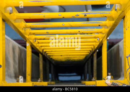 Looking down into a yellow metal ladder attached to the side of the harbour wall in Seahouses, Northumberland England UK Stock Photo