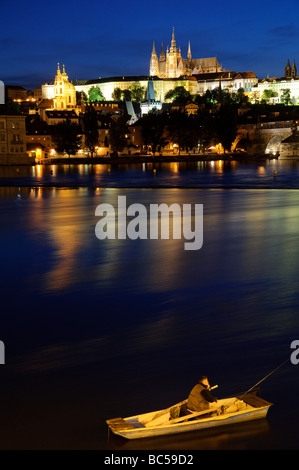 PRAGUE, Czech Republic - Prague Castle at dusk with reflection on Vltava River. The iconic Prague Castle, a symbol of Czech history and power, stands majestically on a hill overlooking the city. It is the largest ancient castle in the world and a UNESCO World Heritage site, drawing countless visitors each year to explore its captivating history and architectural diversity. Stock Photo