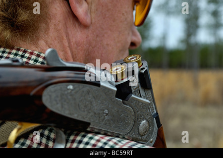 Close Up of Over and Under Shotgun with Open Breech and Loaded Shells on Hunters Shoulder Stock Photo