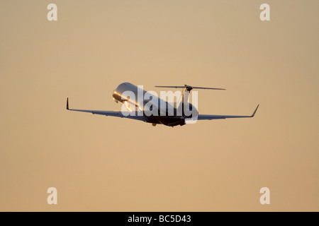 Embraer Legacy 600 private business jet flying in the air against an orange sky at sunset. Corporate aviation. No proprietary details visible. Stock Photo