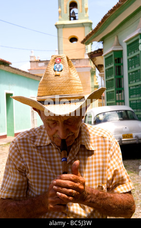 Old man with cigar on cobblestone scene with old car in street scene with old church of the old colonial city Stock Photo