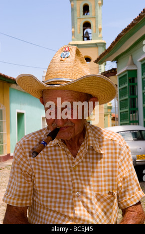 Old man with cigar on cobblestone scene with old car in street scene with old church of the old colonial city Stock Photo