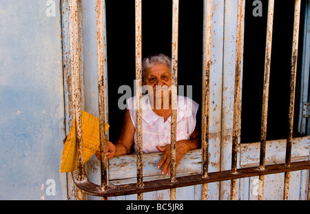 Portrait of old woman behind bars in front in Trinidad Cuba Stock Photo
