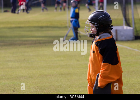 Young lone girl field hockey goal keeper watches the play at the other end Stock Photo