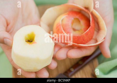 Hands holding a peeled apple and apple peel - Stock Photo