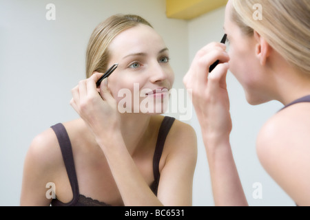 Young woman plucking eyebrows Stock Photo