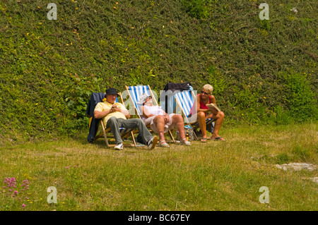 Two Women and a Man Relaxing On Deckchairs On A Grass Bank Stock Photo