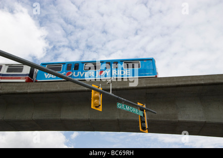 Skytrain passes above Gilmore Avenue, with traffic signal light, in Vancouver Canada Stock Photo