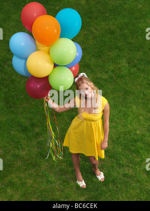 Young smiling woman with a bunch of colorful air balloons in her hand Stock Photo