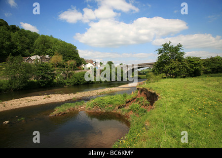 The River Towy flowing under a stone bridge below the hillside town of Llandeilo Stock Photo