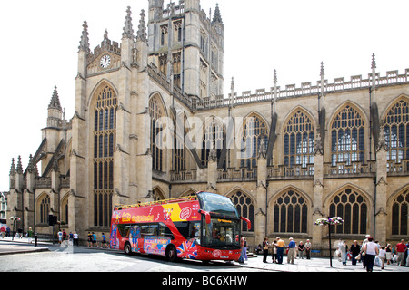 A MODERN OPEN TOP RED TOUR BUS IN FRONT OF THE OLD BATH ABBEY IN SOMERSET, ENGLAND. Stock Photo