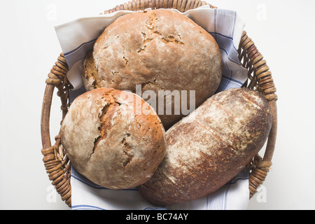 Three rustic loaves of bread in a bread basket - Stock Photo