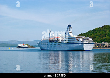 Calmac car ferry Isle of Mull arrives in Oban harbour from Craignure on Mull with passenger cruise ship Astor anchored Stock Photo