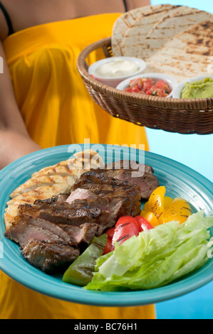 Woman serving Asian platter and basket of accompaniments - Stock Photo