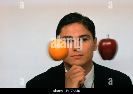 businessman in suit comparing orange & apple Stock Photo