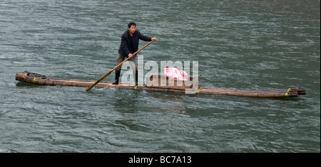 Fisherman rowing bamboo raft in turbulent water River Li Guanxi China Stock Photo