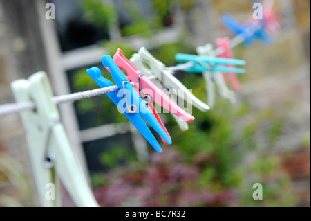 a selection of colourful plastic clothes pegs on a washing line Stock Photo