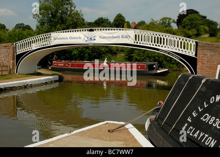 Leisure narrowboat passing Victorian ironwork canal bridge with rally banner at Braunston Marina, Northamptonshire, England Stock Photo