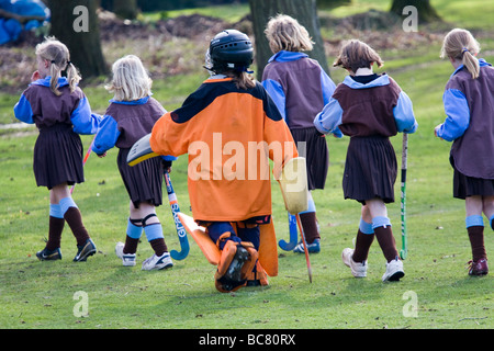 Brandeston Prep young girl field hockey players leave the pitch with the goalie engulfed in her kit.  The school is in beautiful rural Suffolk. Stock Photo