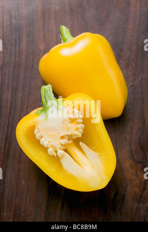 Yellow pepper, halved, on wooden background - Stock Photo