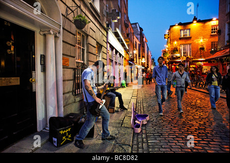 Band busking in cobbled street of Temple Bar nightlife area Dublin Republic of Ireland Stock Photo