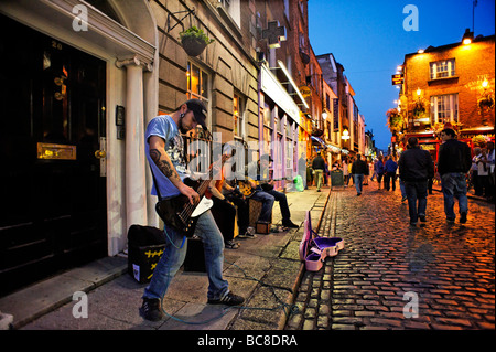 Band busking in cobbled street of Temple Bar nightlife area Dublin Republic of Ireland Stock Photo
