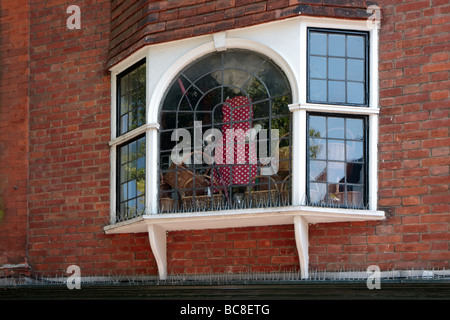 Close-up of a yellow bay window with lace curtains and a 