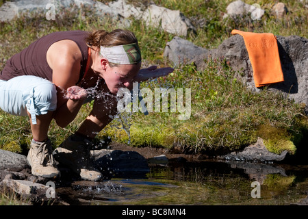 A woman washing her face in a smal creek along the Wonderland Trail, Washington State. Stock Photo