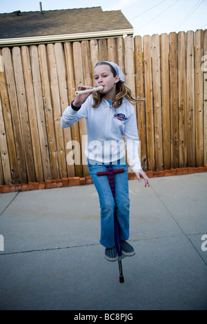 A girl playing recorder and jumping on a pogo stick Los Angeles County California United States of America Stock Photo