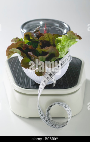Bowl of lettuce with tape measure on scales - Stock Photo