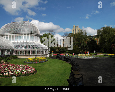 Palm house designed by Charles Lanyon in the botanic gardens, Belfast,  with the new library at Queen's University Stock Photo