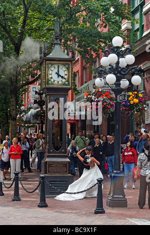 Wedding Couple kissing each other in front of steam clock in Gastown Vancouver City Canada North America Stock Photo