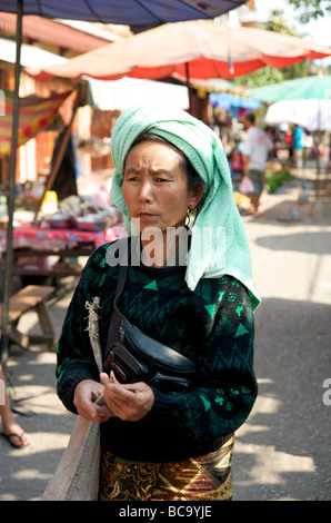 A Lao woman wearing a green towel headdress out shopping in the daily fresh food market of Luang Prabang Laos Stock Photo