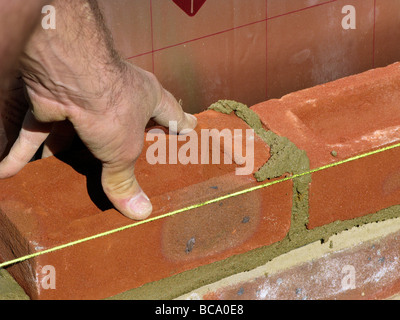 builder / construction worker working on a brick wall cementing bricks in  (new property or extension) Stock Photo