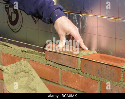 builder / construction worker working on a brick wall cementing bricks in (new property or extension) Stock Photo