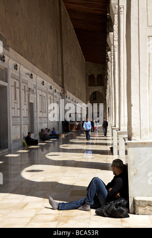 Tourists and visitors resting in the shade under arches at the Great Umayyad Mosque, Damascus, Syria Stock Photo