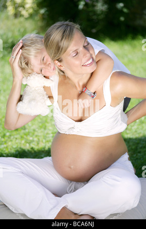 Boy (4-5 years) embracing pregnant mother from behind, Styria, Austria Stock Photo