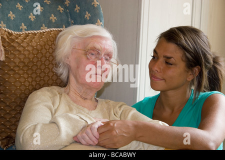 young woman consoling geriatric lady with bruised face in home Stock Photo