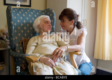 woman consoling dying old lady with bruised eye in nursing home Stock Photo