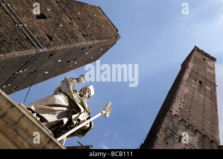 looking up at the two towers with the statue of st petronius by brunelli in piazza ravegnana bologna italy Stock Photo