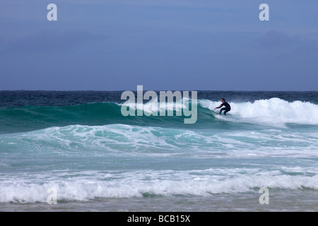 Surfing waves off Porthmeor beach in summer sun St Ives Cornwall England UK United Kingdom GB Great Britain British Isles Europe Stock Photo