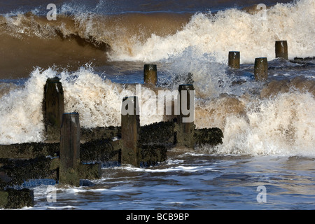 Breaking waves around the groynes, Walcott, Norfolk Stock Photo