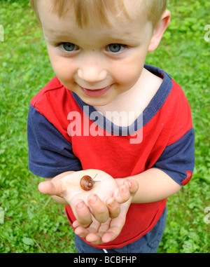 Child kid blond boy hand holding Helix pomatia Snail Europe garden Stock Photo