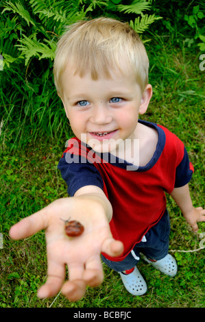 Child kid blond boy hand holding Helix pomatia Snail Europe garden Stock Photo