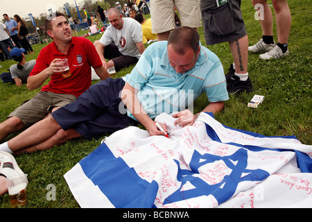 English football fans writing messages on an Israeli flag in Tel Aviv before a match between Israel and England. Stock Photo