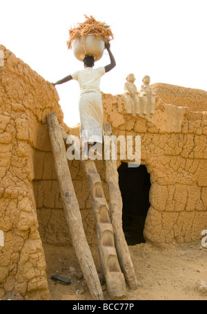 Burkina Faso. Lobi country. Sukala or traditional animist house.Women carrying millet. Stock Photo