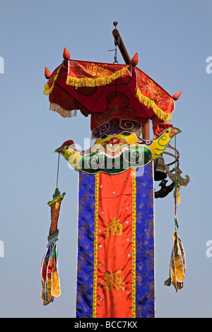 Decorated pole with umbrella roosters and banner erected outside the temple next to One Pillar Pagoda in Hanoi Stock Photo
