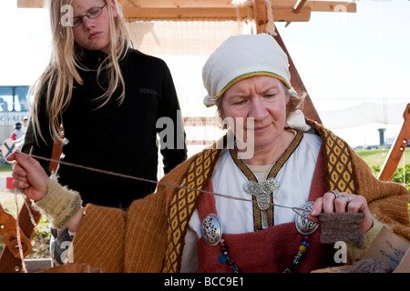 Woman knitting, she is wearing traditional Viking era clothes. Viking festival in Hafnarfjordur, Greater Reykjavik Area, Iceland Stock Photo