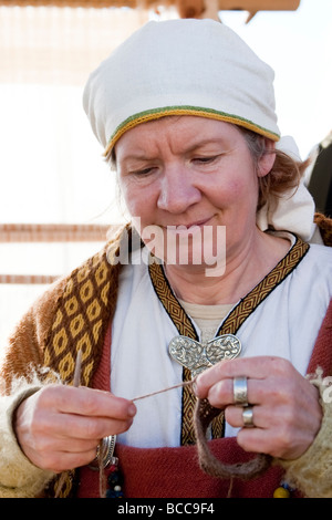 Woman knitting, she is wearing traditional Viking era clothes. Viking festival in Hafnarfjordur, Greater Reykjavik Area, Iceland Stock Photo