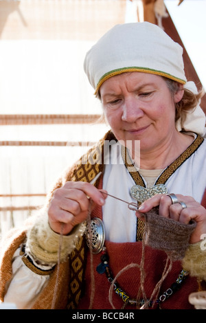 Woman knitting, she is wearing traditional Viking era clothes. Viking festival in Hafnarfjordur, Greater Reykjavik Area, Iceland Stock Photo